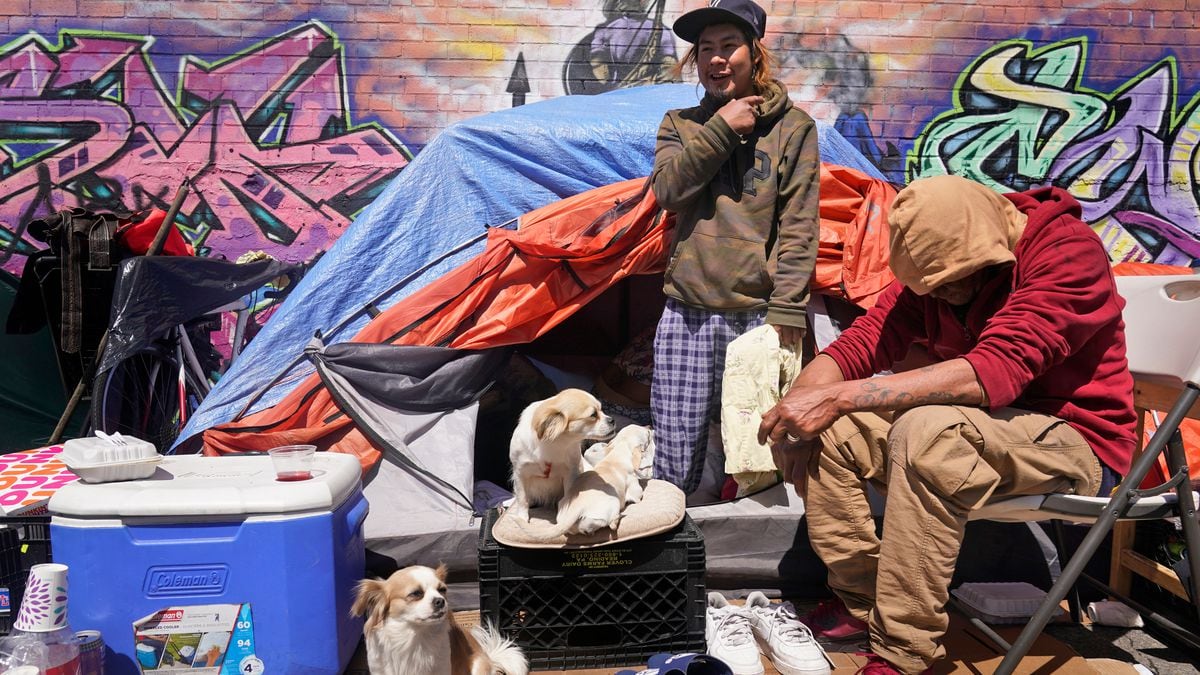 Lucio Lopez, left, talks with friends as he stands in a tent that is part of a homeless...