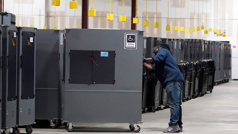 FILE - A worker returns voting machines to storage at the Fulton County Election preparation...